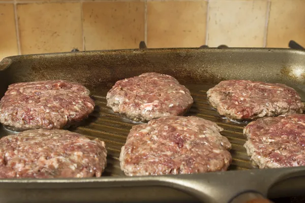 Raw burgers on a griddle