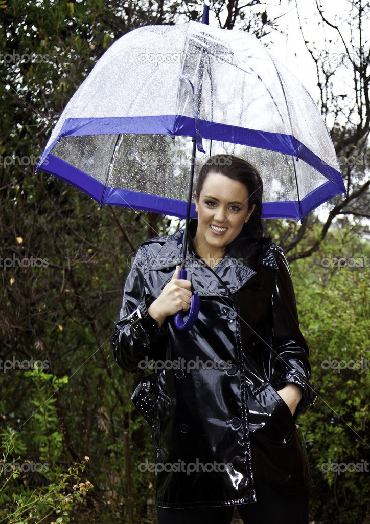 Attractive young woman dressed for wet weather in shiny black raincoat