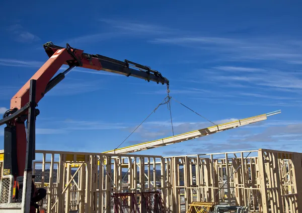 Crane lifts roof trusses onto new houses under construction — Stock Photo, Image