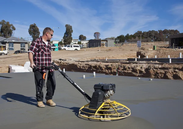 Workman smoothing newly poured concrete for new house — Stock Photo, Image