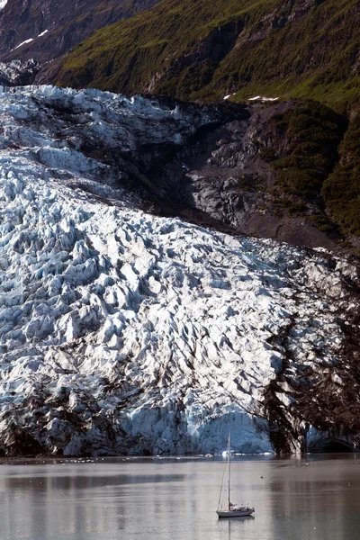 Kleine jacht overschaduwd door de massale gletsjer — Stockfoto