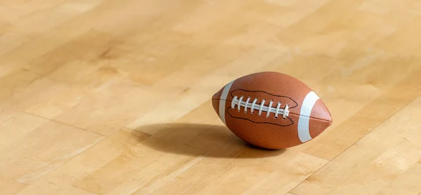 天然照明付きの堅木張りの床のアメリカのサッカーボール ワークアウトのオンラインコンセプト 水平スポーツポスター グリーティングカード ヘッダー ウェブサイト — ストック写真