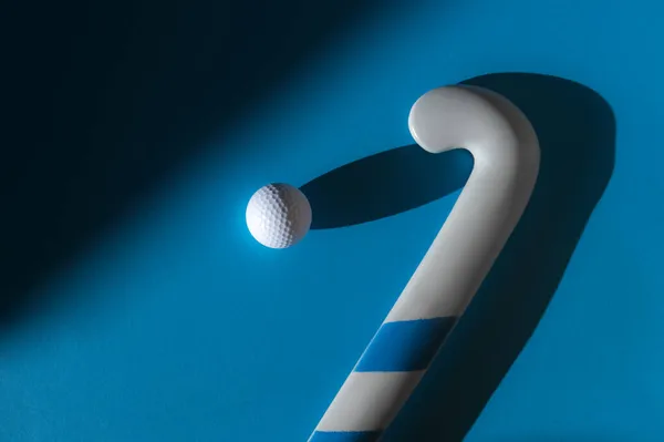 iField hockey stick and white ball with natural lighting on blue background. Sport team concept. Horizontal sport theme poster, greeting cards, headers, website and app