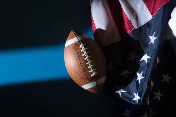 American football ball and flag with natural lighting on blue background. Horizontal sport theme poster, greeting cards, headers, website and app
