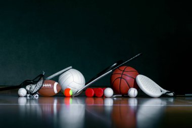 Spor aletleri, raketler ve toplar parke kort zemininde koyu arkaplan ve fotokopi alanı ile. Yatay eğitim ve spor afişi, tebrik kartları, başlıklar, websitesi