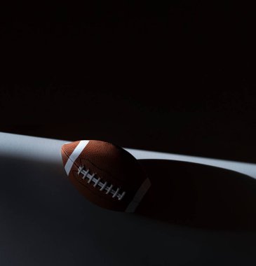 Siyah arka planda doğal ışıklandırması olan Amerikan futbol topu. Yatay spor temalı poster, tebrik kartları, başlıklar, web sitesi ve uygulama