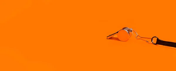 Sports whistle on orange background. Concept - sport competition, referee, statistics, challenge. Basketball, handball, futsal, volleyball, soccer, baseball, football and hockey referee whistle