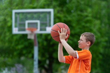 Park kortunda basketbol oynayan bir çocuk. Spor yaşam tarzı, eğitim, kamp, boş zaman, tatil kavramı. Yatay spor temalı poster, tebrik kartları, başlıklar, web sitesi ve uygulama