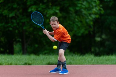 Tenis kortunda tenis raketi olan bir çocuk. Küçük çocuklar için eğitim, sağlıklı çocuklar. Yatay spor temalı poster, tebrik kartları, başlıklar, web sitesi ve uygulama