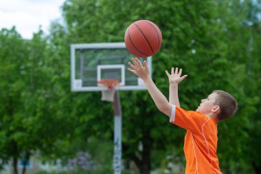 Park kortunda basketbol oynayan bir çocuk. Spor yaşam tarzı, eğitim, kamp, boş zaman, tatil kavramı. Yatay spor temalı poster, tebrik kartları, başlıklar, web sitesi ve uygulama