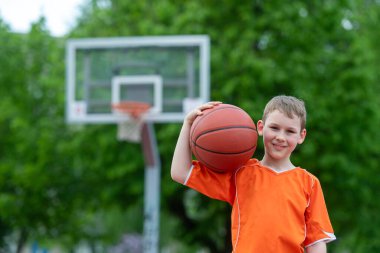 Park kortunda basketbol oynayan bir çocuk. Spor yaşam tarzı, eğitim, kamp, boş zaman, tatil kavramı. Yatay spor temalı poster, tebrik kartları, başlıklar, web sitesi ve uygulama