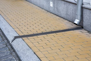 Granit taşla kaplanmış bir binanın ön cephesi fırtına borusuyla kanalizasyon kanalına taştan kaldırımlar ve kaldırımlardan yapılmış demir ızgarayla kaplı kaldırımlar, eski şehrin gelişimi, hiç kimse.