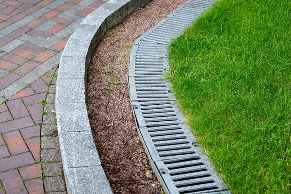 Demir Kanalizasyon Izgarası Yol Kenarında Yeşil Çimenler Taş Çakıl Taşlarıyla — Stok fotoğraf