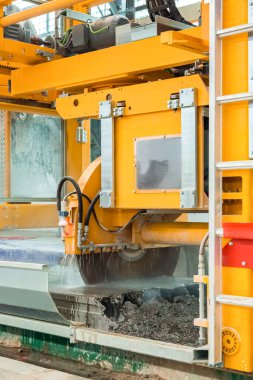 beton kesme makinesi, güçlendirilmiş beton ürünleri dairesel testereyle kesme makinesi ve suyu serin bir yere püskürten hortumlar ürünün parçalara ayrıldığı yere yakın detaylar..