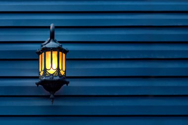 Mavi ahşap bir duvara monte edilmiş sarı cam gölgeli demir retro fener, akşam aydınlatmasının dekoratif mimari objeleri, ön cephede fotokopi alanı ile birlikte..
