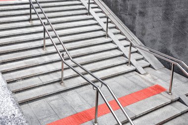 granite staircase with stone steps and stainless steel iron handrail descent to the underground crossing, entrance to the subway with tactile tiles and a ramp for the disabled, top side view, nobody.