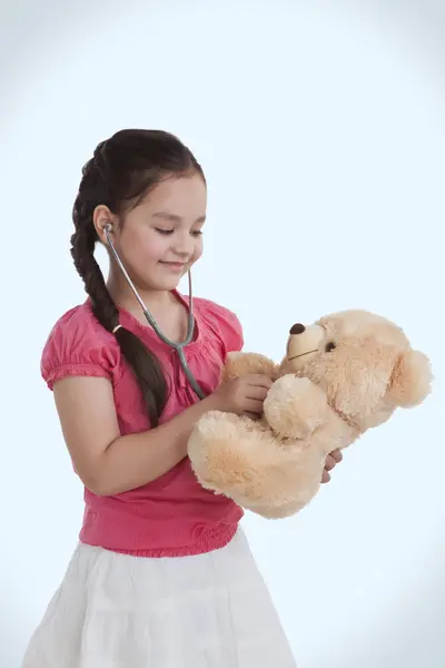 Flicka som leker doktor med en nallebjörn — Stockfoto