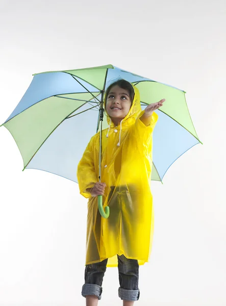 女の子はレインコートを着ていると、傘を差し — ストック写真