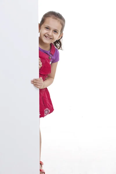 Brincalhão menina espreitando através de placa branca — Fotografia de Stock