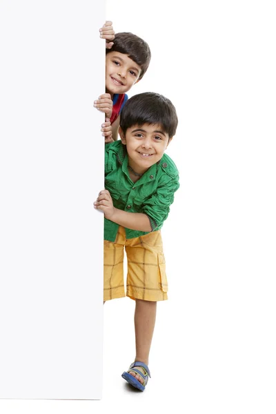 Boys peeking through blank billboard — Stock Photo, Image