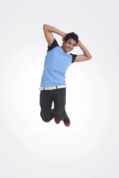 Retrato de cuerpo entero del joven con las manos detrás de la cabeza saltando — Foto de Stock