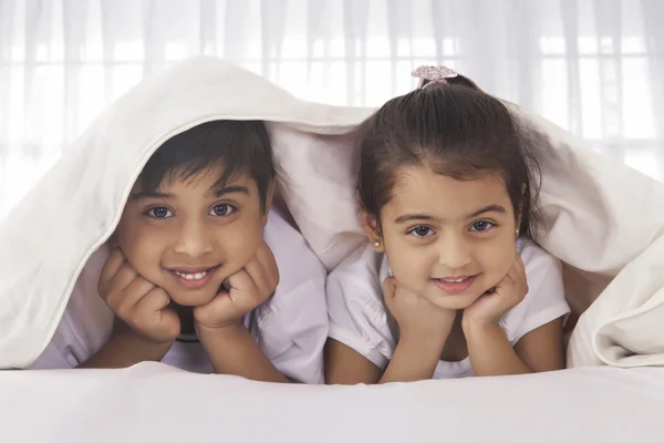 Irmãos bonitos sob cobertor na cama — Fotografia de Stock