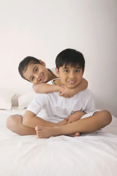 Retrato de chica feliz abrazando al hermano desde atrás en la cama —  Fotos de Stock