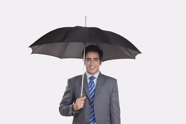 Joven hombre de negocios escondido bajo paraguas — Foto de Stock