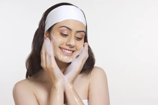 Uśmiechnięta kobieta mycia twarzy — Zdjęcie stockowe