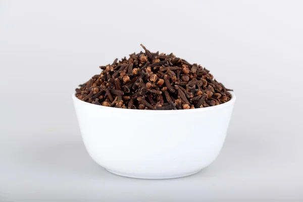 Cloves in white bowl with white background — Stock Photo, Image