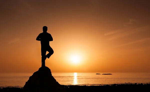 Человек, занимающийся йогой на пляже во время восхода солнца — стоковое фото