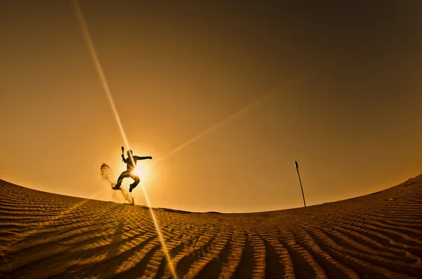 Silueta de un hombre saltando con la flecha en la mano, desierto de Dubai, Emiratos Árabes Unidos — Foto de Stock