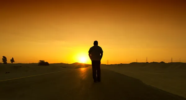 Hombre caminando en la carretera con el estado de ánimo relajado. Camino del desierto en Dubai, Emiratos Árabes Unidos —  Fotos de Stock
