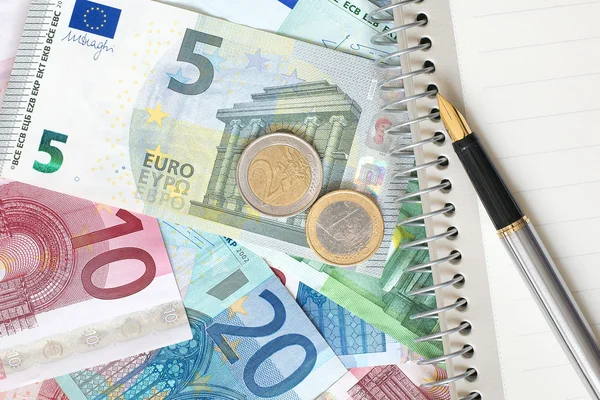 Notepad with a pen on the background of Euro banknotes. — Stock Photo, Image