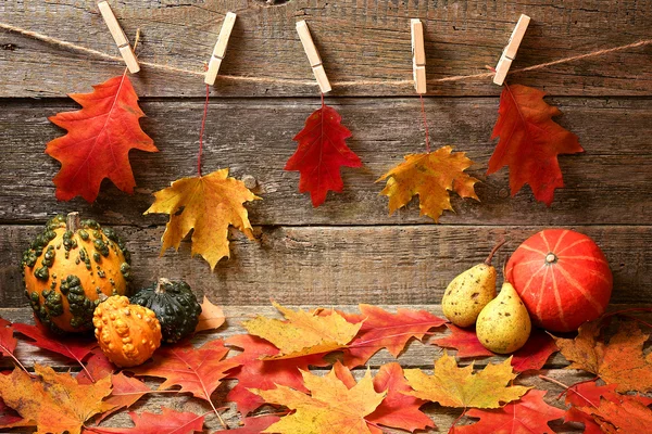 Autumn abstraction. Leaves and pumpkins on the old wooden background. — Stock Photo, Image