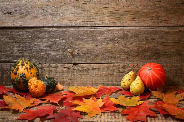 Autumn abstraction. Leaves and pumpkins on the old wooden background. — Stock Photo, Image