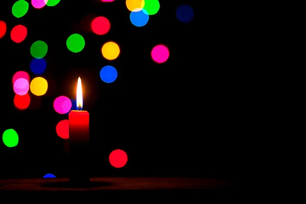Červená svíčka na černém pozadí s barevnými kuličkami. — Stock fotografie