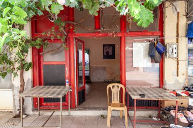 Türkiye 'nin eski Esilova kasabasında iki masa ve ahşap sandalyeli eski kırmızı cam kapı. Küçük Türkçe atölyesi