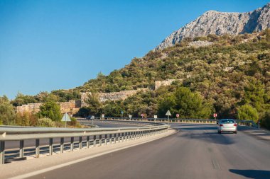 Antik duvar, otobanın yanında, hindinin içinde. Tarihi kalıntılar. Sıcak bir yaz gününde, dağların ve kayaların arasında hindi otobanı. Turizm ve dinlenme.