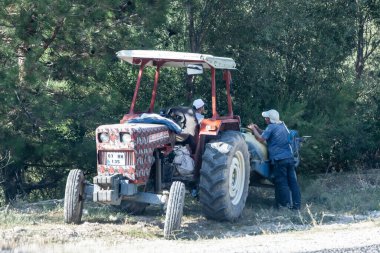 Antalya, Türkiye - 08. - 28. 2021: Üç woker 'lı eski turuncu traktör