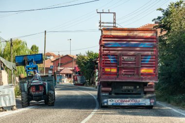 Antalya, Türkiye - 08. - 28. 2021: Türkiye 'de kamyonların ve küçük bir traktörün sürdüğü bir köy caddesi, virajdan dışarı bakan bir tarayıcı kamyonu