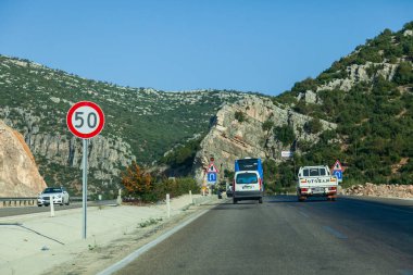 Antalya, Türkiye - 08. - 28. 2021: Türkiye 'de dağlar boyunca uzanan yol, otoyol boyunca giden arabalar dağları geçiyor, hız sınırı tabelası 50, dağlar ve yakınlardaki otoyol,