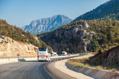 Antalya, Türkiye - 08. - 28. 2021: Türkiye 'de dağlar boyunca uzanan yol, otoyol boyunca dağlar, dağlar ve yakınlardaki otoyol boyunca giden arabalar. Logolu otobüs Coral Travel