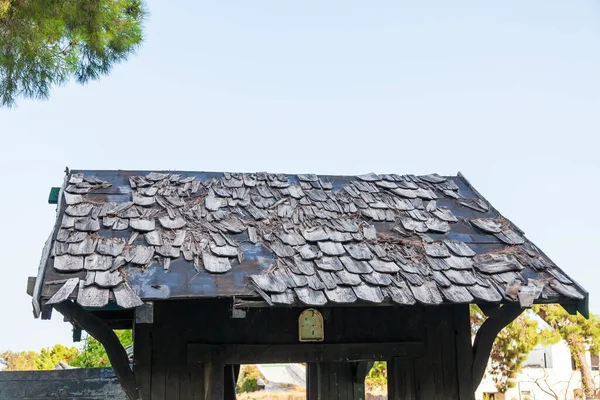 Damaged old wooden roof tiles on a pitched roof.