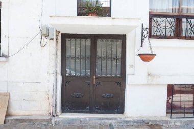 Binanın ön cephesine yakın plan ve antika bir siyah tahta kapı. Kiremitler ve eski ahşap bir kapı..