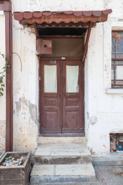 Binanın ön cephesine yakın çekim ve antika tarzı kahverengi ahşap kapı. Kiremitler ve eski ahşap bir kapı..