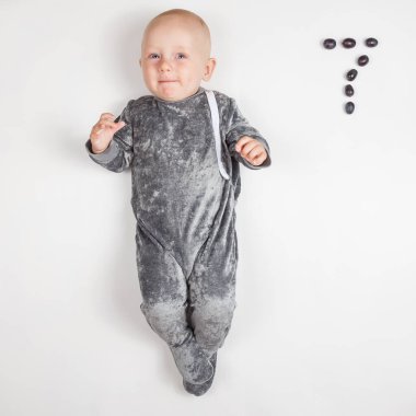 Gülümseyen mutlu yeni doğmuş bebek. Gri elbiseli, yedi aylık bebek. Parlak, havadar fotokopi odası çocukluğu..