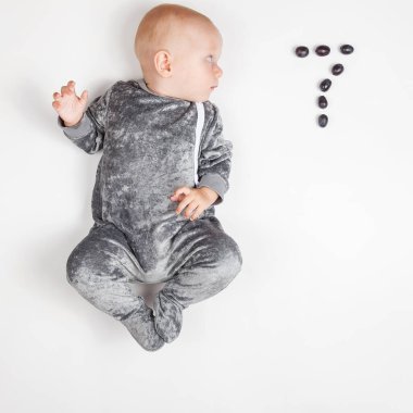 Gülümseyen mutlu yeni doğmuş bebek. Gri elbiseli, yedi aylık bebek. Parlak, havadar fotokopi odası çocukluğu..