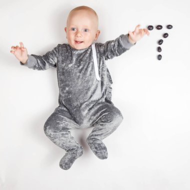 Gülümseyen mutlu yeni doğmuş bebek. Gri elbiseli, yedi aylık bebek. Parlak, havadar fotokopi odası çocukluğu..