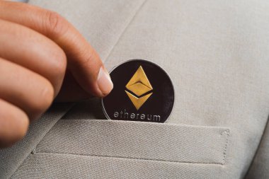 Altın Ethereum ETH 'de dahil olmak üzere Kripto para birimi takım elbise çantasındaki iş adamı kahverengi takım elbise ceketi giyen parmaklarıyla topluyor. Bana güzel arka plandaki liflerin detaylarını ver.